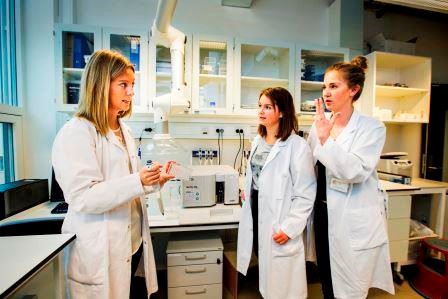 Tre kvinner i hvite frakker i et laboratorium 