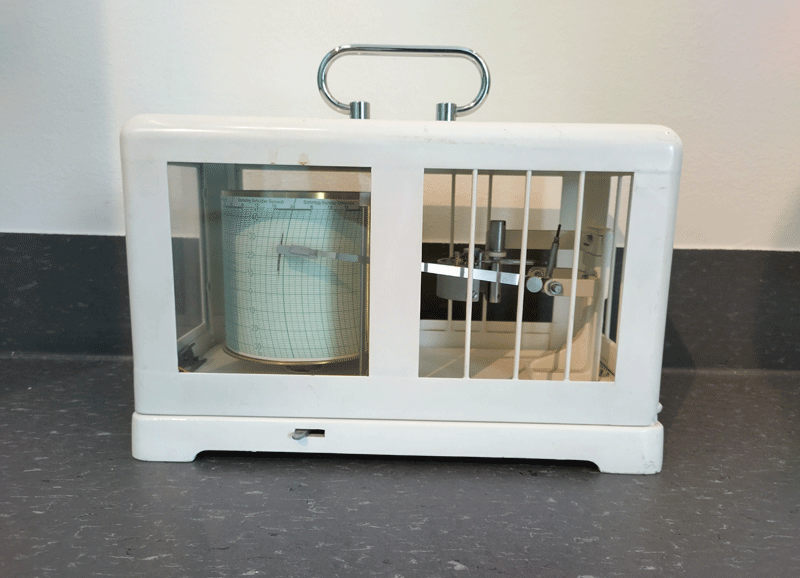Hvit rektangulær boks i metall, med åpninger på sidene og håndtak på toppen
