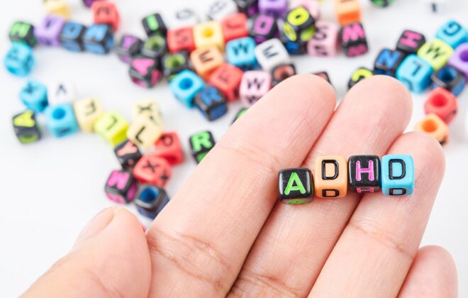 Hånd med fire terninger og ADHD bokstaver