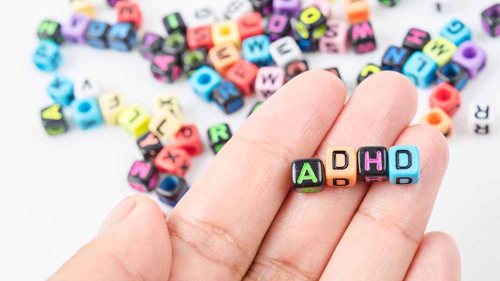 Hånd med fire terninger og ADHD bokstaver