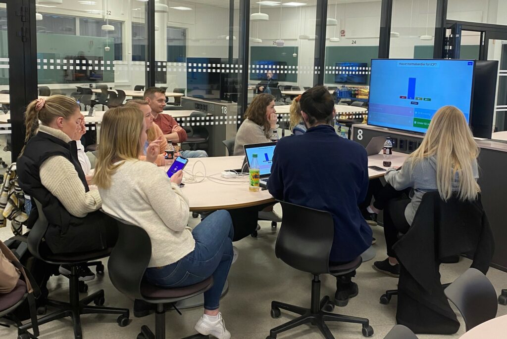 Studenter samarbeider i klasserom med skjermer.