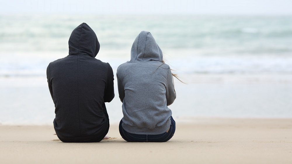 To mennesker sitter på strand