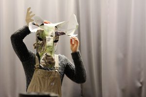 Student putting on a moose head made of paper. Photo.