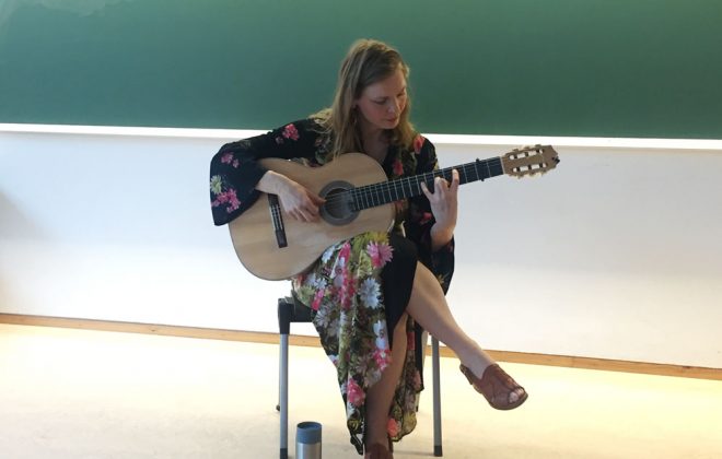 Flamencogitarist Bettina Flater sitter på en stol og spiller gitar