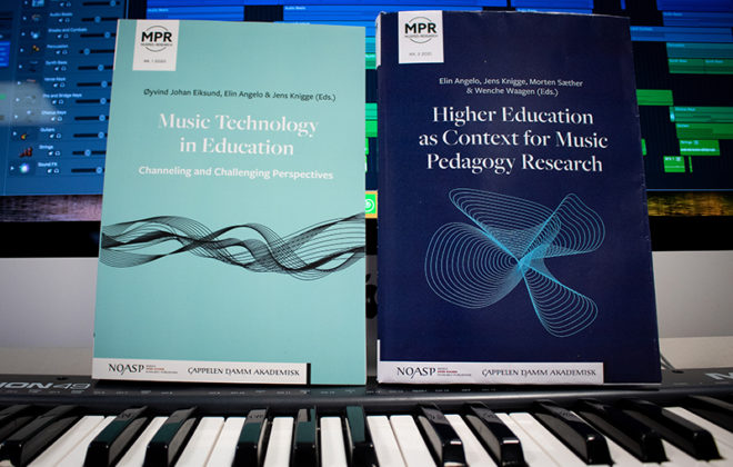 To bøker som står oppå tangenter, foran en datamaskin med musikkprogram. Foto