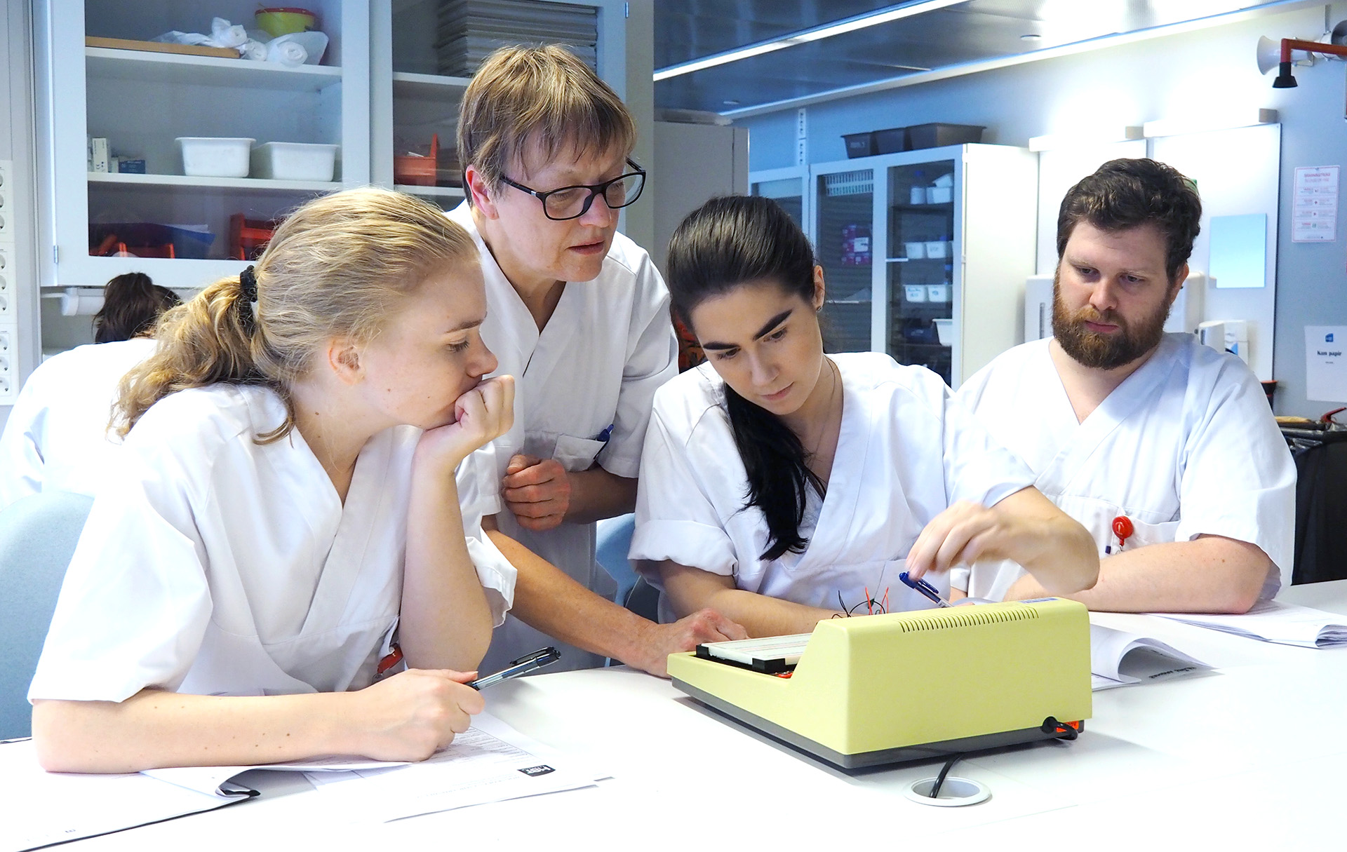 Tre bioingeniør-studenter på lab med lærer. Foto