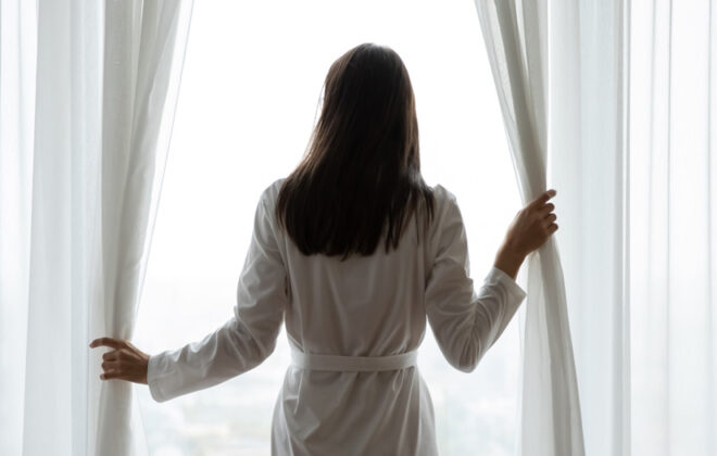 woman opening curtains on hotel room, admiring the view. photo