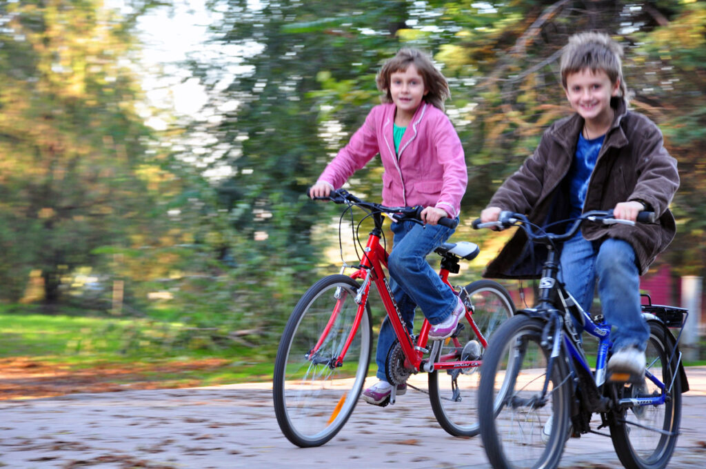 jente og gutt på hver sin sykkel i fart på asfalt. foto