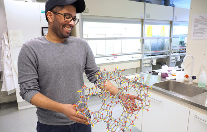 PhD candidate showing an atomic model. Photo