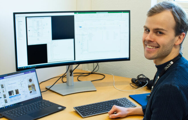 Smiling man in front of two pc screens. photo