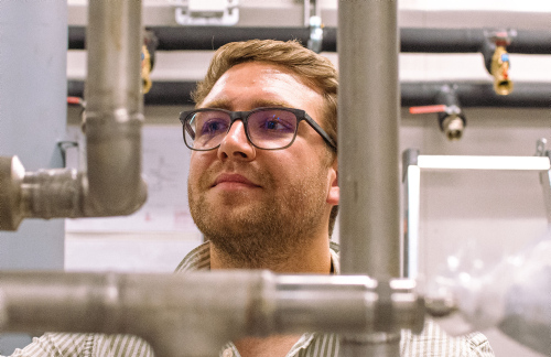man with glasses looking at metal pipes in the lab. photo
