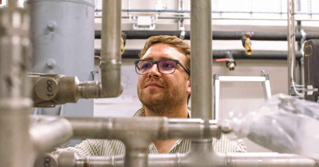 man with glasses looking at metal pipes in the lab. photo