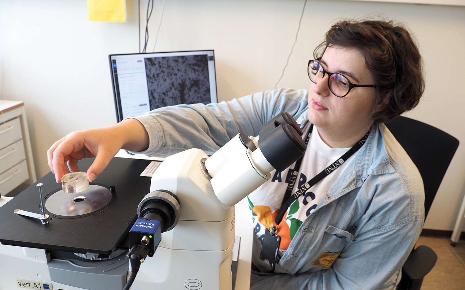 Kvinne som legge objekt på mikroskop. Foto