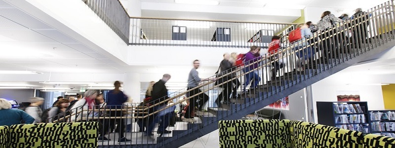 Students walking up the stairs in the library photo from side angle, looking slightly upwards