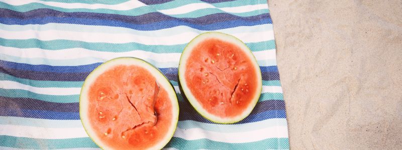 Photo of two halfed watermelons on a stripy beach towel