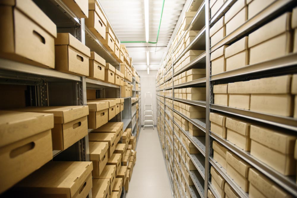 Archival boxes with photographs on shelves in an archive