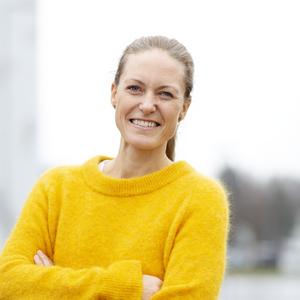 Smilende kvinne i gul genser. 