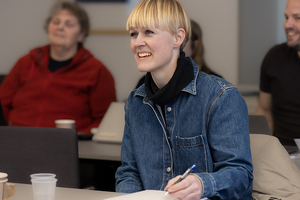 Smilende kvinne i klasserom med voksne studenter i bakgrunnen