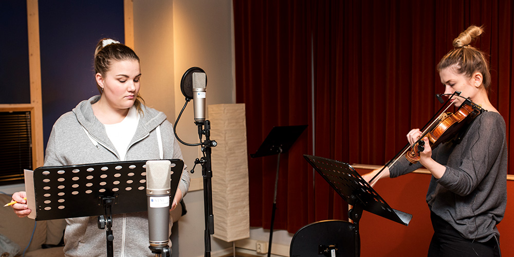 To unge kvinner i studio, en vokalist og en fiolinist