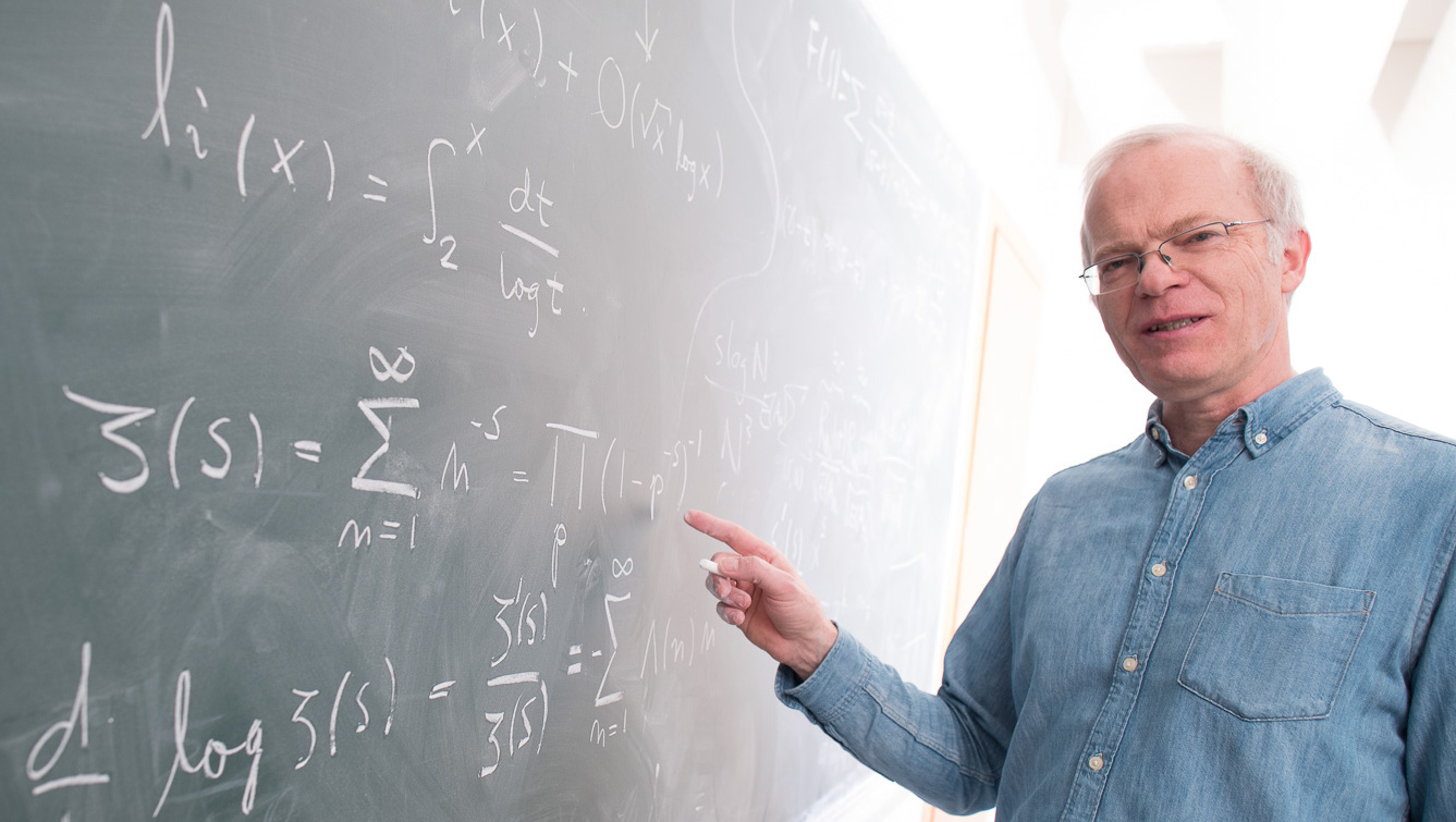Matematiker Kristian Seip skriver på tavle. Foto.