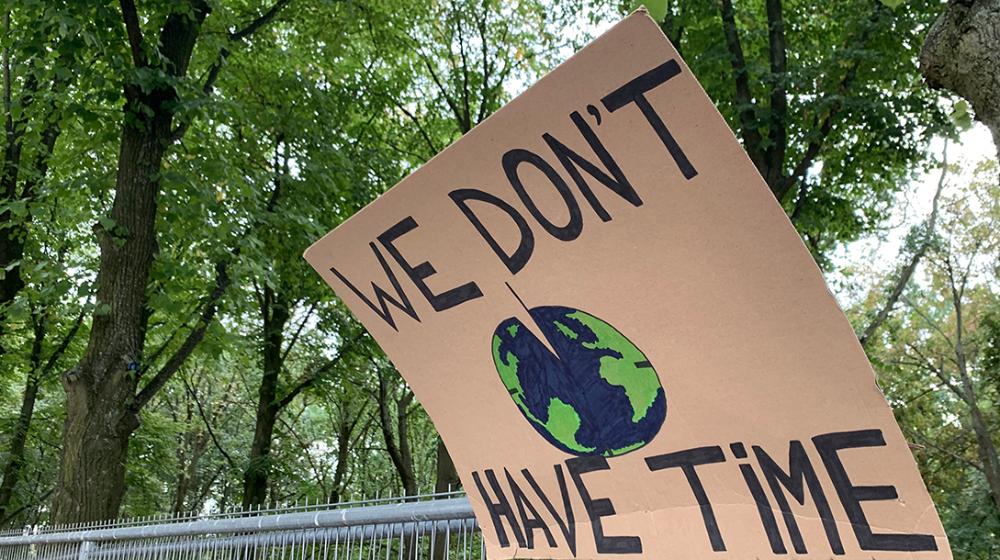 Foto av plakat med jordklode og teksten "We don't have time"