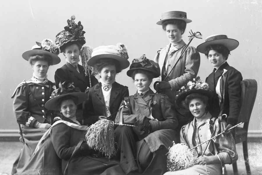 seks damer kledd i hatt og kjole