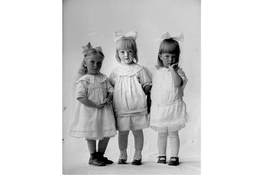 Tre små jenter i fine kjoler og store sløyfer i håret, 1917
