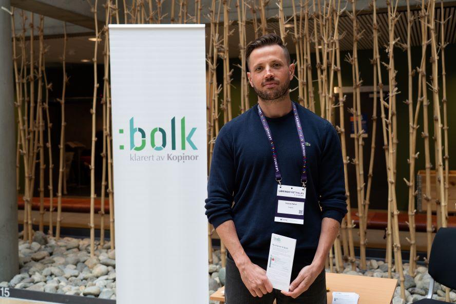 En mann står ved siden av en rollup med teksten Bolk, klarert av Kopinor