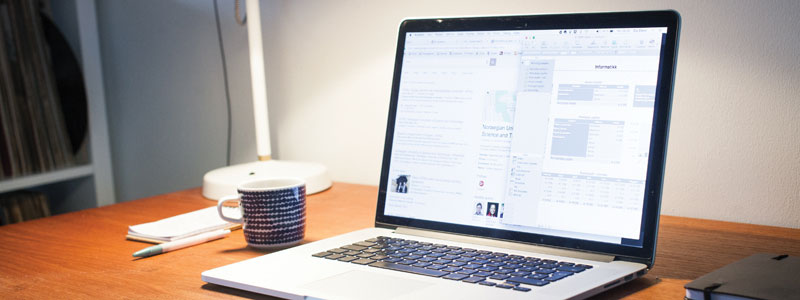 Bilde av en kontorpult med PC og en kaffekopp.