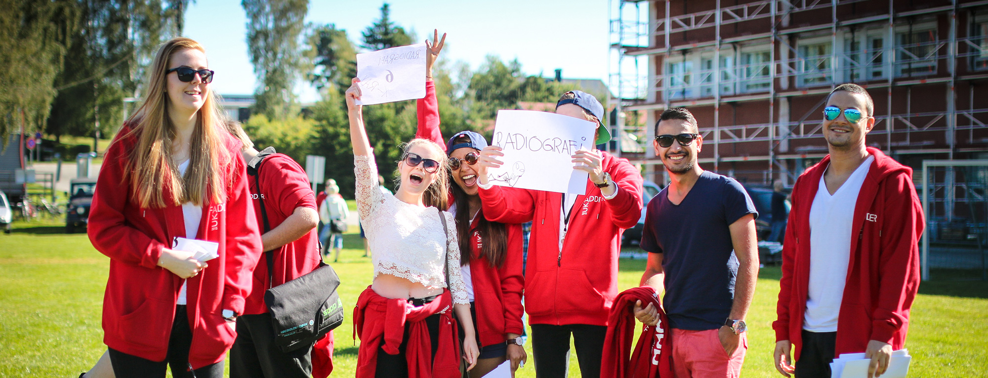 Studenter står ute på campus Gjøvik og smiler. Foto.