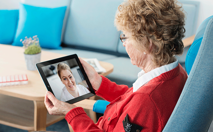 eldre dame kommuniserer med helsepersonell via iPad