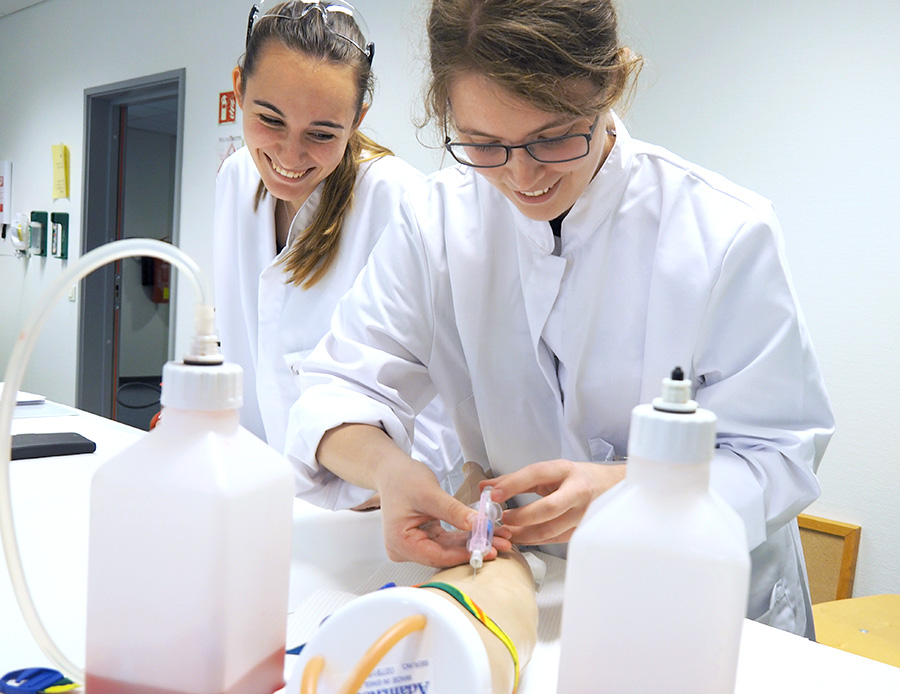 To studenter som tar en blodprøve på en dummy-arm på laben. Foto