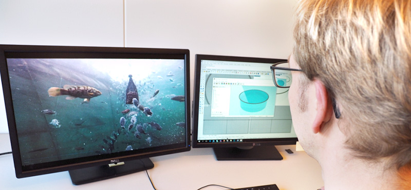 Forsker foran en dataskjerm med fisk ved et oppdrettsanlegg. Photo