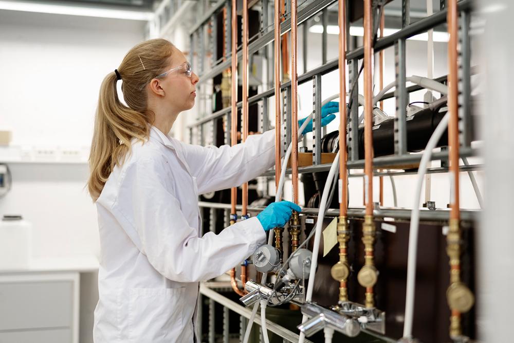 Jente med hestehale står ved en rørrigg i et laboratorium 