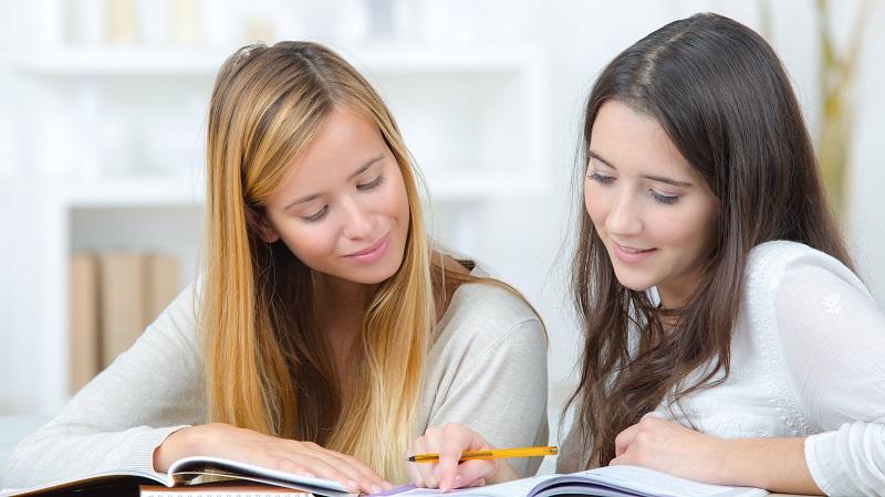 To jenter studerer en tekst.  Foto: Colourbox