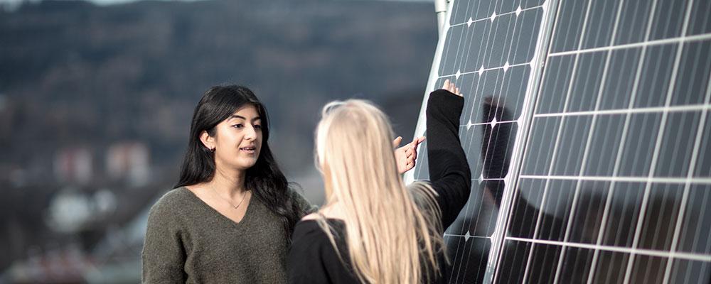 To studenter ved solcellepanel. Lenke til NTNU Energi Team Solenergi sin nettside.