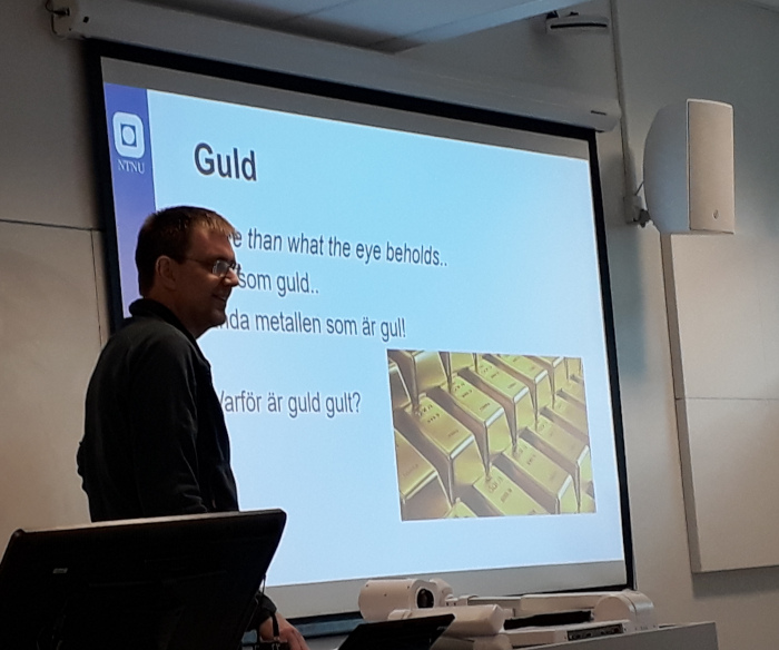 Jonas Persson foran en powerpoint-presentajson om gull. Foto.