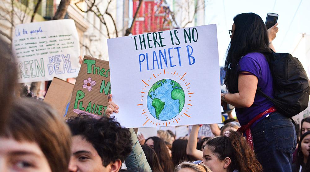 Klimademonstranter holder opp plakater. Den nærmest leser "There is no planet B". Foto