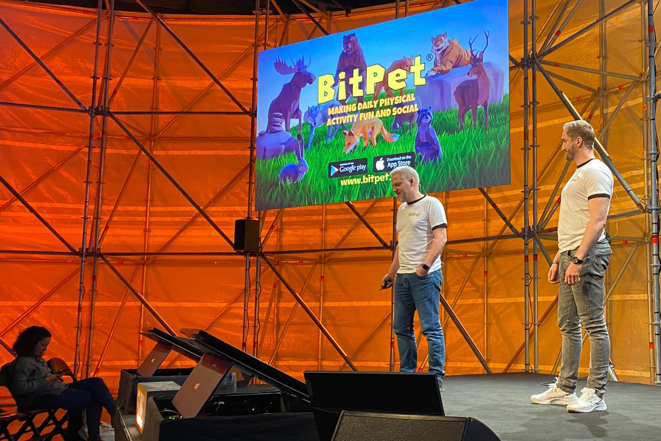 to personer står på en scene, på en stor skjerm bak dem står det BitPet