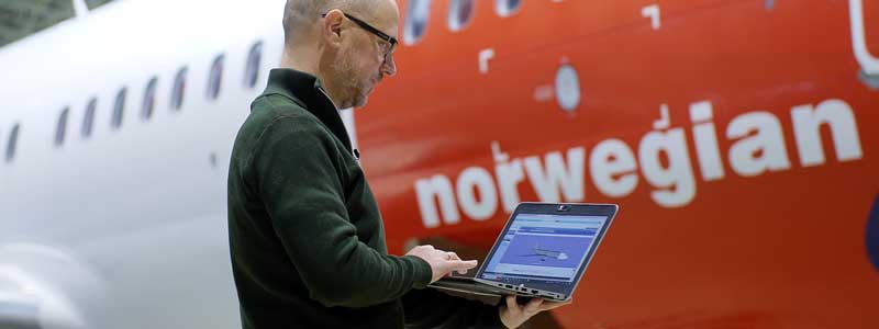 Flyingeniør kontolerer fly på pc foran et norwegian-fly 