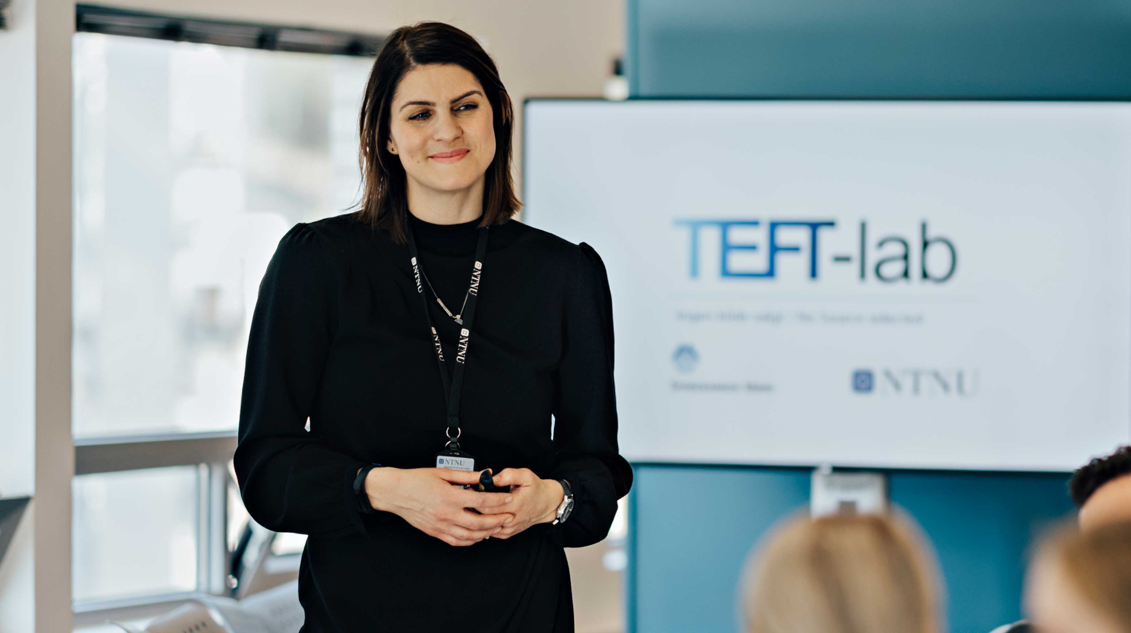 Kvinne holder presentasjon foran skjerm hvor det står TEFT-lab