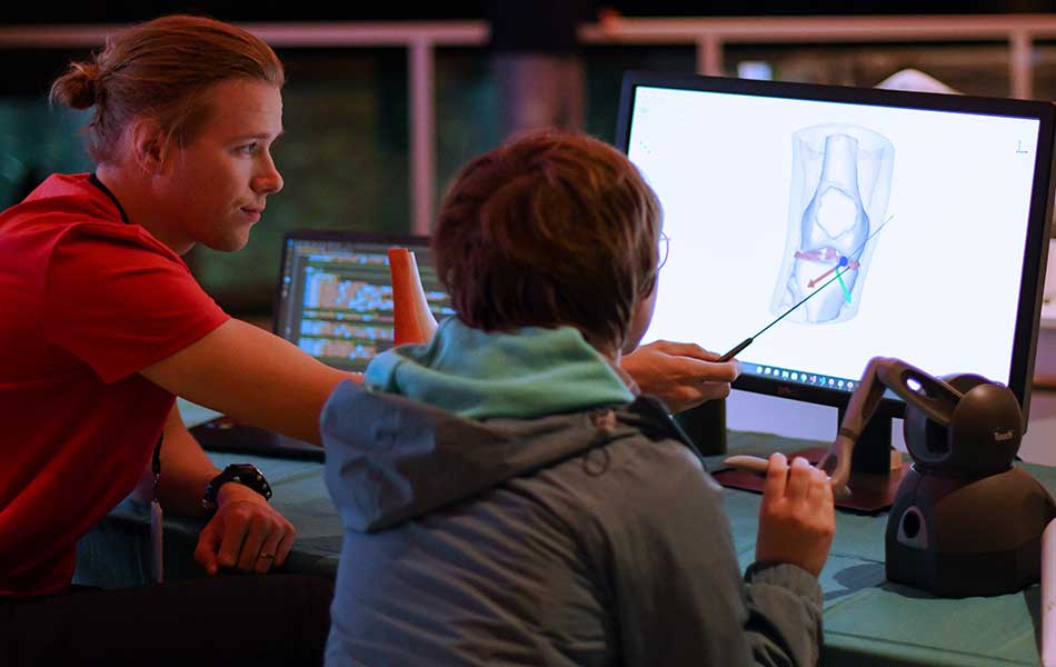 To studenter ser på en pc-skjerm med programvare de har laget som gjør oss i stand til å simulere operasjoner