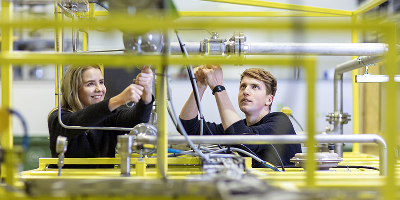 To studenter jobber med et rørsystem i laboratorie