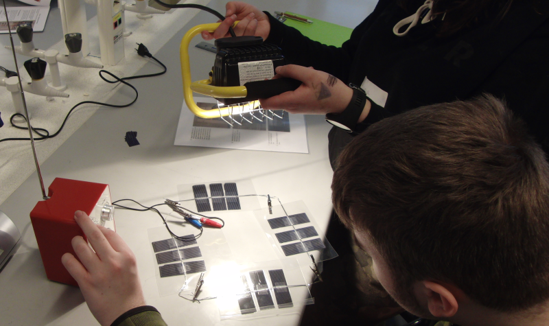 To elever som prøver å få lyd i en radio ved hjelp av strøm fra solceller. Foto.