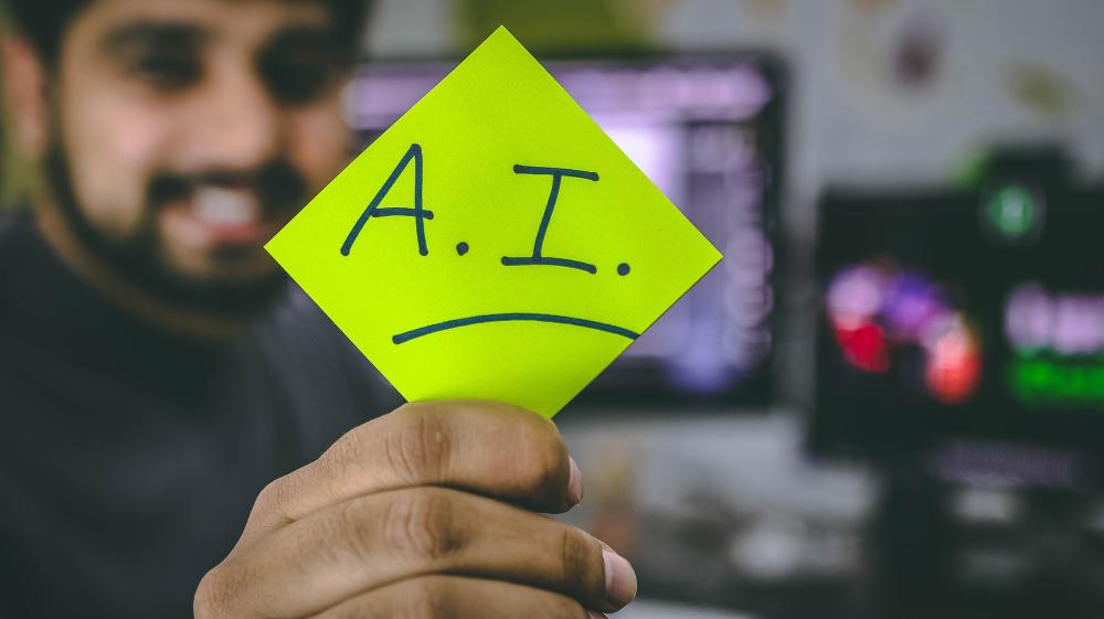 Person holding green piece of paper with the letters A.I. written on. Photo.